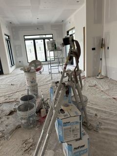Worker sanding drywall joint compound smooth on an interior wall